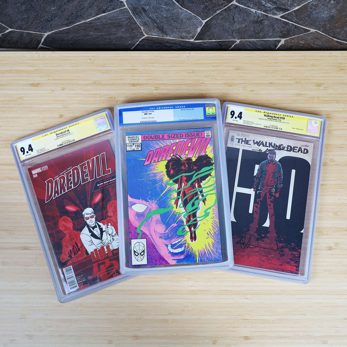 Three graded comics protected with translucent BCW slab bumpers, overhead view